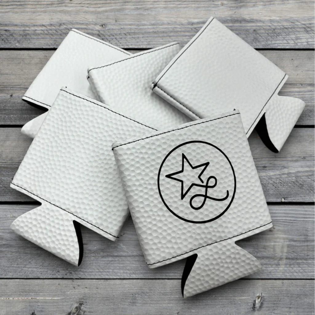 Flat lay of multiple white golf ball leatherette can coolers showing texture